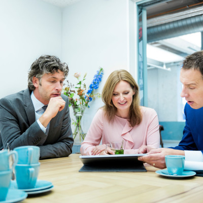 Drie mensen in gesprek aan vergadertafel