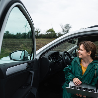 Ondernemer zit in auto met laptop op schoot